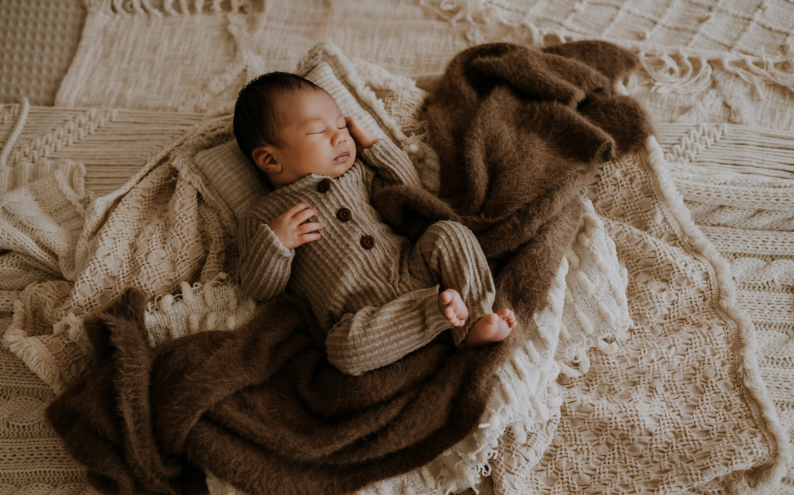 A baby boy laying on a bed sleeping wrapped in blankets in fort worth, texas