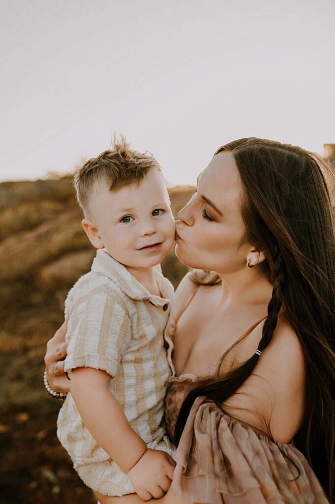 A mom and her toddler son are cuddling in Lawton Oklahoma as the mother kisses her sons cheek.