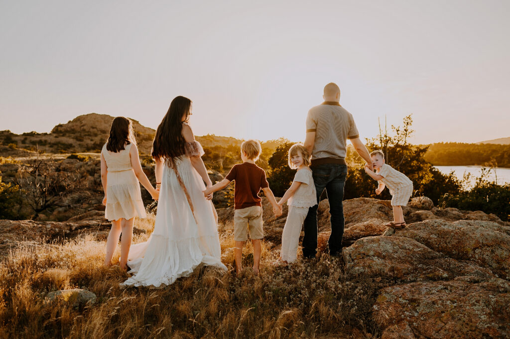 A family of six holding hands and looking at the mountains in the Wichita Refuge in Lawton, oklahoma.