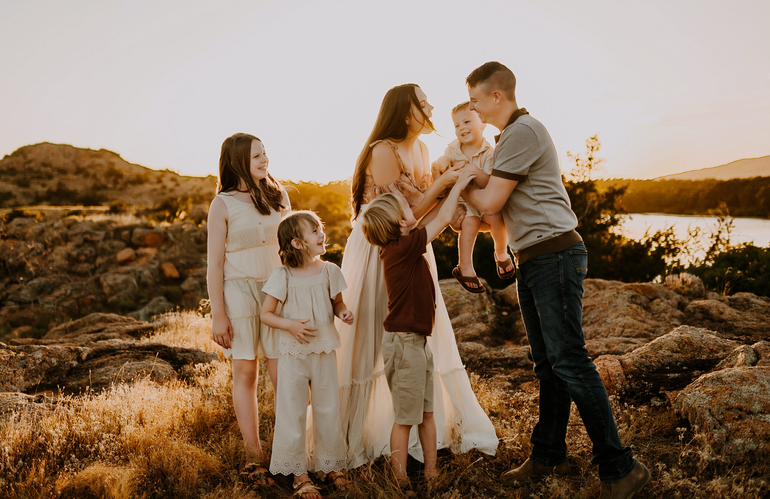 A family of six standing in the middle of the wichita mountains of oklahoma laughing with one another in boho wardrobe