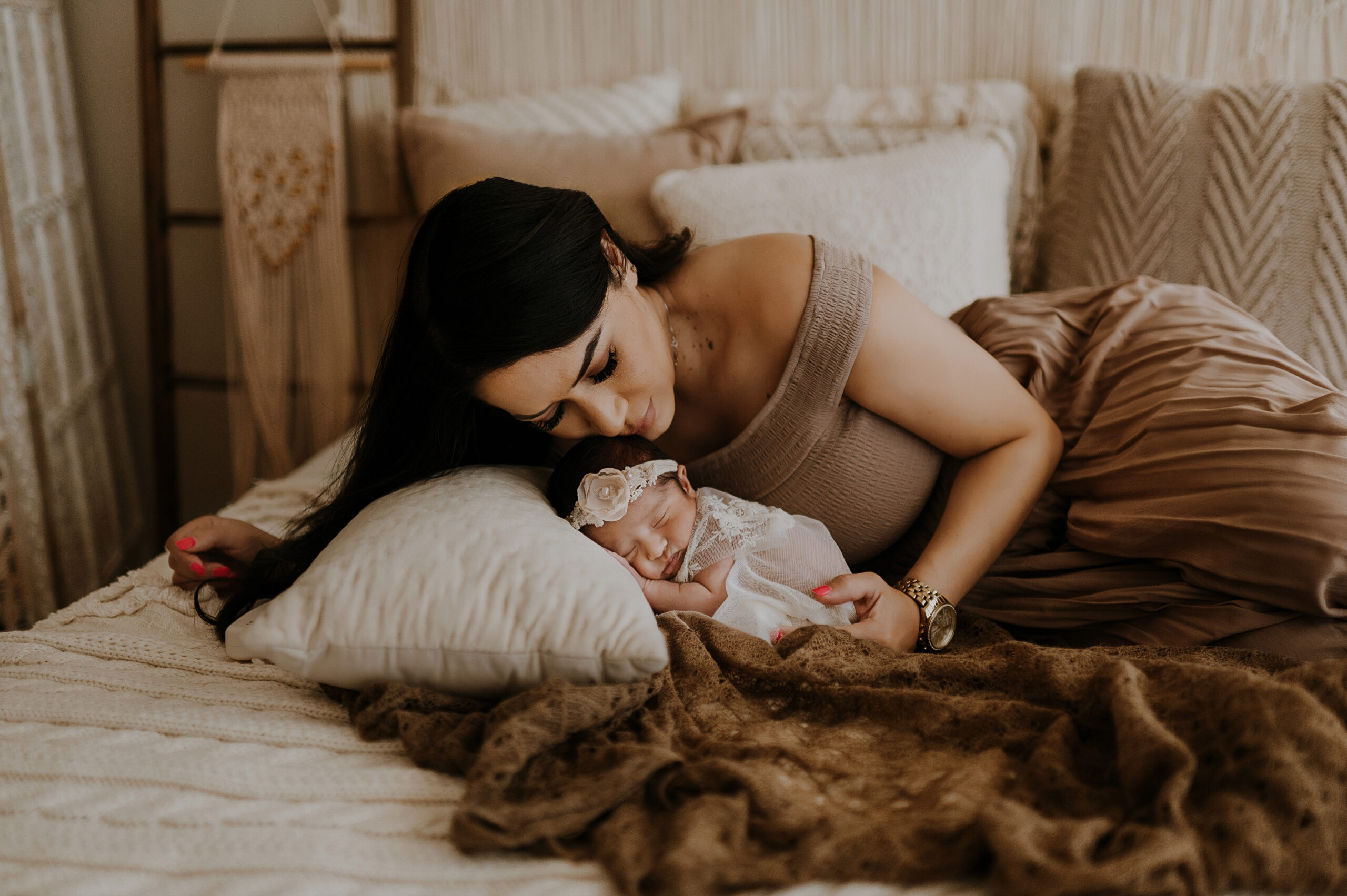 A mom lays next to her newborn baby girl and places her cheek on her head in a fort worth, texas studio