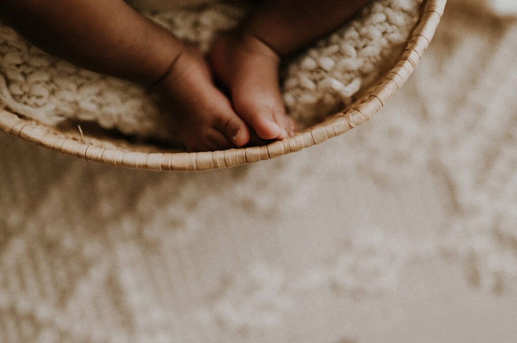 A basket holding a baby and focus on their toes at a boho studio in fort worth, texas