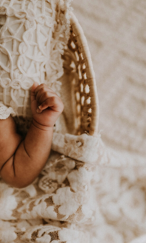 A close up of a baby's arm in a baby moses basket at a fort worth, texas boho photo studio