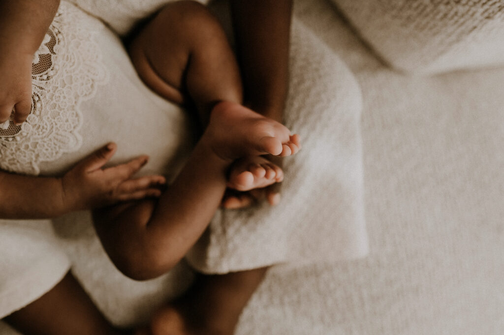 A toddler girl holding her newborn sister and holding her toes in fort worth, texas