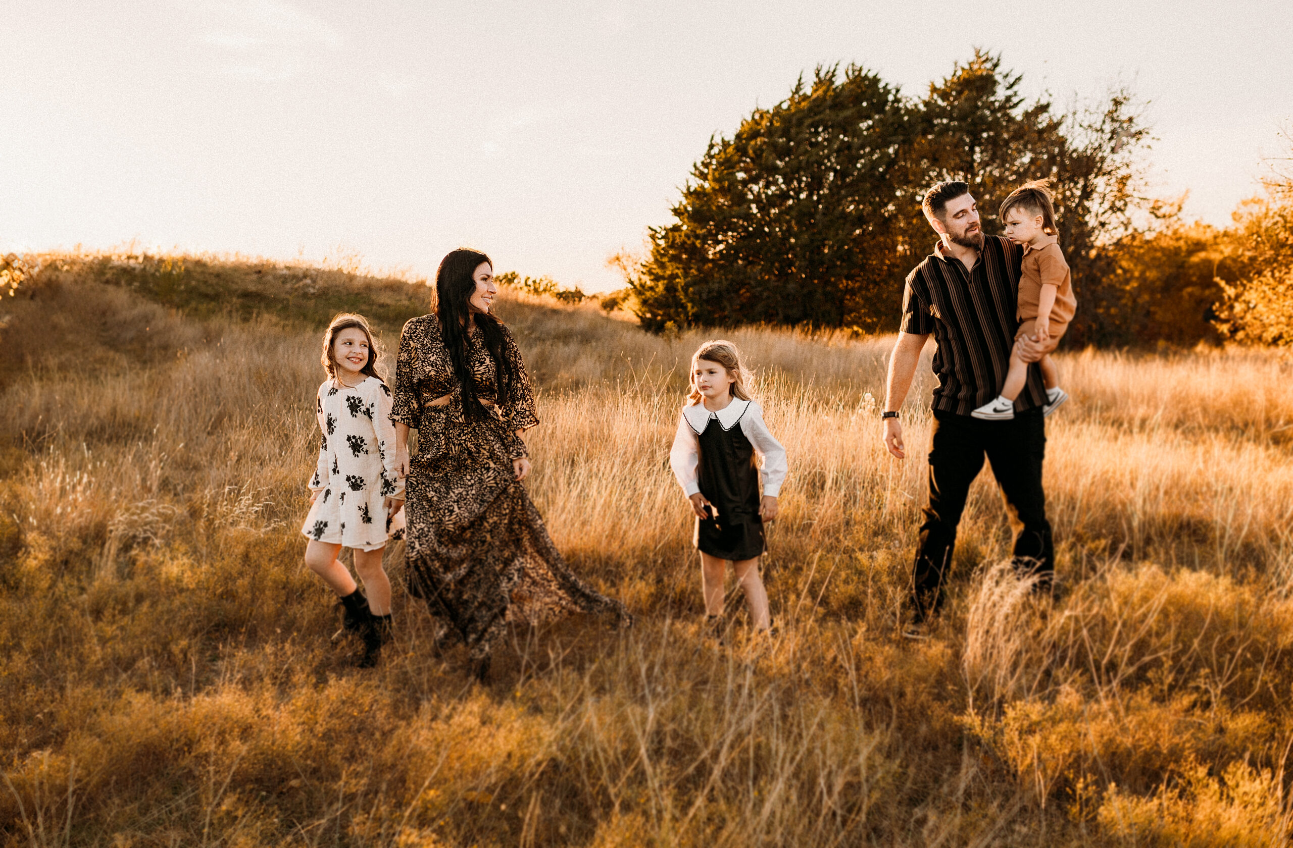 A family of five are walking accros a golden yellow field at arbor hills in plano, texas