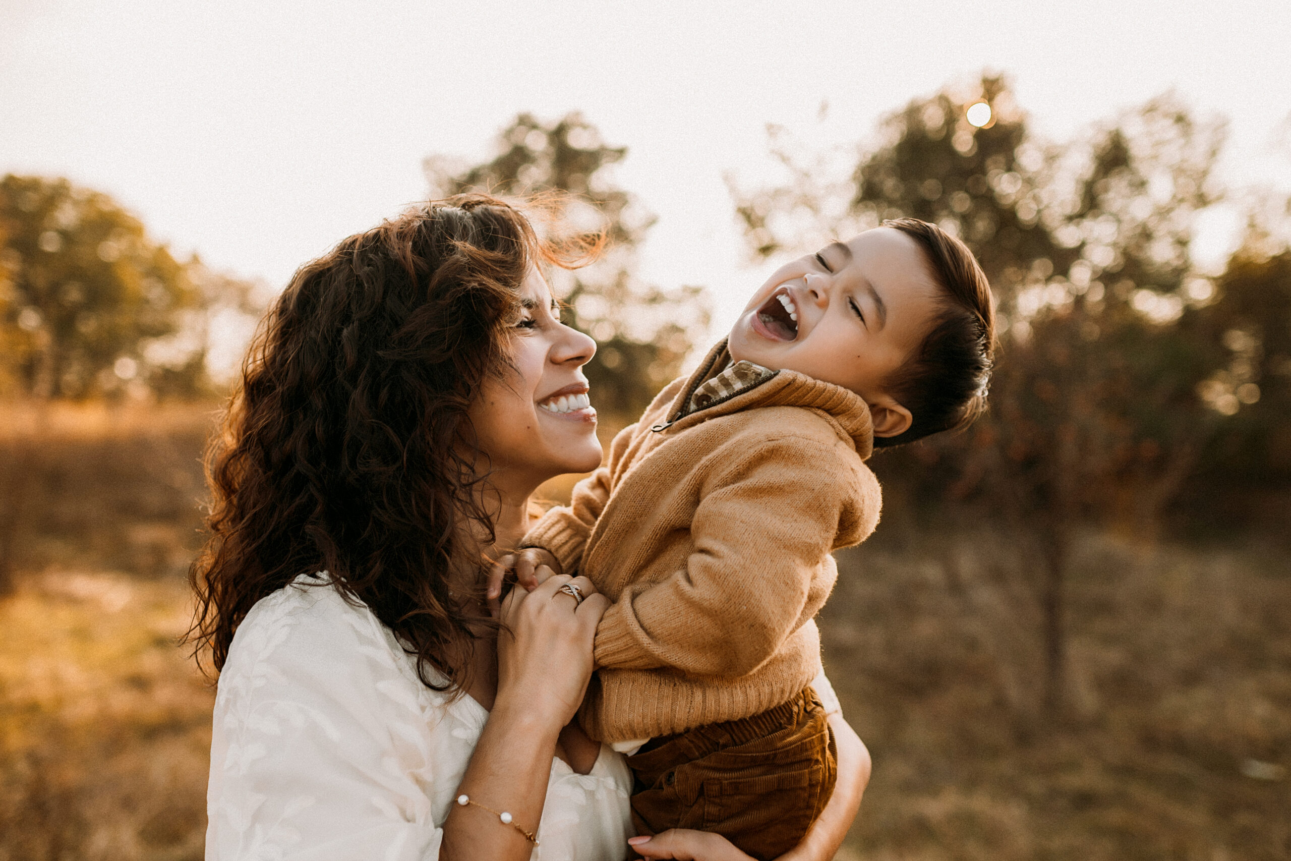 A little boy laughing really hard as his mom holds him in her arms in flower mound, texas